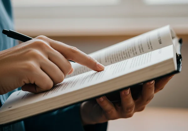 Person using finger as a pacer to guide reading on a book